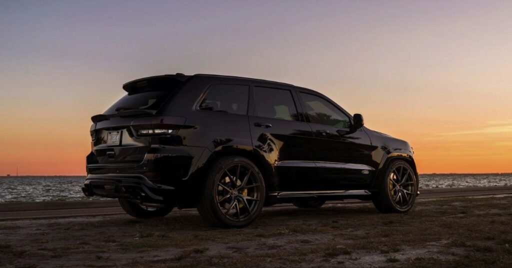 full black jeed grand cherokee on a beach on sunset